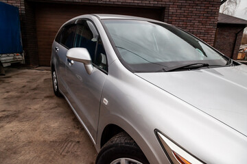 Close-up of the side right mirror and window of the car body silver sedan on the street parking after washing and detailing in auto service industry. Road safety while driving