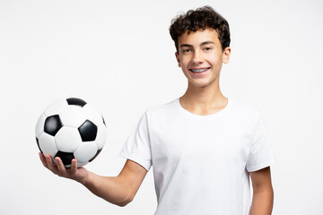 Portrait of handsome teenage boy wearing white t shirt holding soccer ball looking at camera, fan