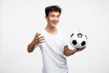 Smiling teenage boy, fan in white t shirt holding soccer ball, cheering, watching football match