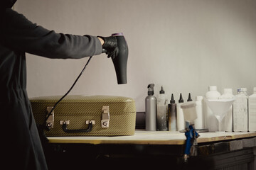 The workplace of the master restorer. Repair of leather goods. Blow-drying of the repair part on a leather suitcase. A hair dryer in women's hands.