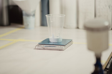 Defrosting a plastic cup on a scale. The workplace of the restoration master. The hands of the master in black gloves