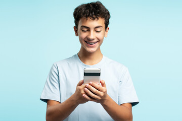Portrait of happy boy holding mobile phone, text message, chatting, watching video standing