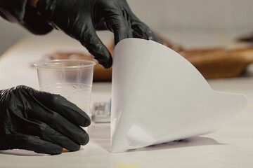 Woman in black protective gloves takes a funnel for paint in car workshop