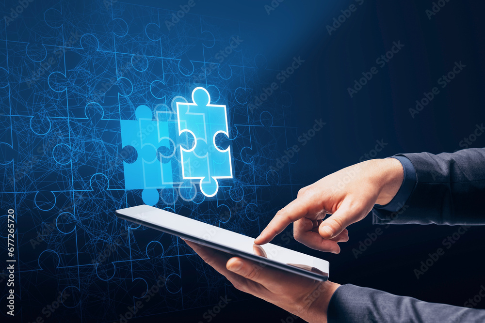 Poster close up of businessman hand pointing at cellphone with abstract glowing jigsaw puzzle on blue backg