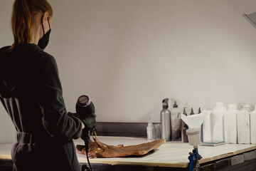 The workplace of the master restorer. Repair of leather goods. Blow-drying of the repair part on a leather bag.