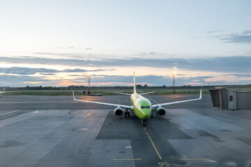 The airplane stands at the airport at sunset. The plane is preparing to take off.