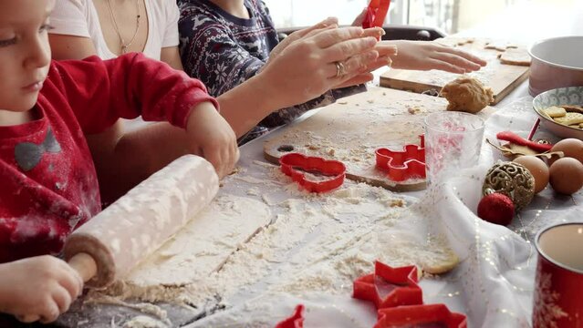 Closeup of family hands rolling dough and cutting cookies and ginger bread for Christmas celebrations. Winter holidays, celebrations and party