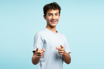 Portrait of excited attractive boy wearing stylish casual clothes showing fingers looking at camera