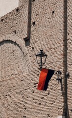 Parete storica in mattoni con bandiera al vento e legata ad un lampione vecchio © albasu