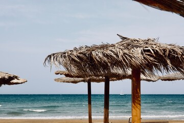 Ombrelloni in legno e copertura in makuti al vento e con sfondo del mare