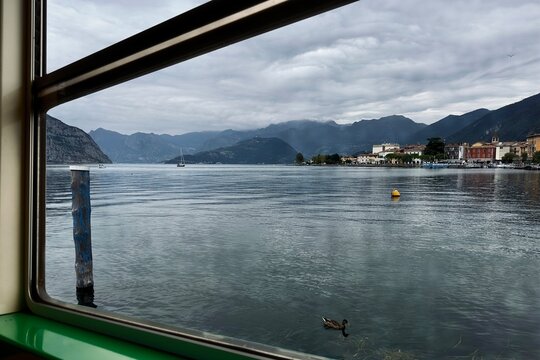 Vista del lago attraverso il finestrino di una nave traghetto con lo sfondo di montagne