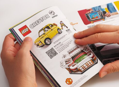 Tambov, Russian Federation - December 21, 2021 Woman browsing Lego catalog on a page with Lego Creator Expert sets. Close-up.