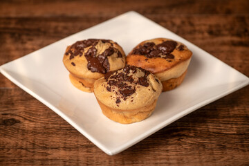 Homemade banana and chocolate muffins from the oven on a white plate with melting chocolate.