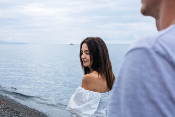 Portrait of a beautiful brunette girl at sea, with a guy in the background