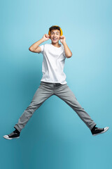 Portrait of happy teenage boy in stylish casual clothes wearing yellow hat looking at camera jumping