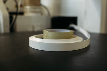 Filling the machine with a PVC edge for edging parts made of chipboard.