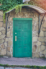 An old wooden door on the stone wall of a village house. Green closed door with copy space. High...