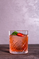 cocktail with mint and strawberries in a glass glass on a gray background