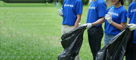 A group of Asian volunteers pick up trash on the lawn after an outdoor activity.