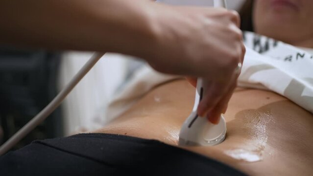 Close-up, a female doctor doing an ultrasound of the stomach. A patient in the clinic. Medical examination of the abdominal cavity using an ultrasound machine.