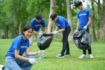 Obraz premium A group of Asian volunteers pick up trash on the lawn after an outdoor activity.