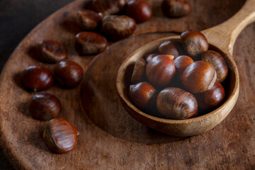 Fresh sweet edible chestnuts in wooden bowl, closeup