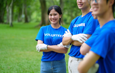 A group of Asian volunteers pick up trash on the lawn after an outdoor activity.