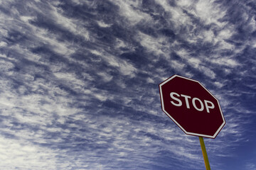 Red STOP sign, with yellow wood pole with coudy sky background in Brazil. Traffic Regulatory...