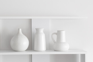 white ceramic vases on wooden shelf on white wall