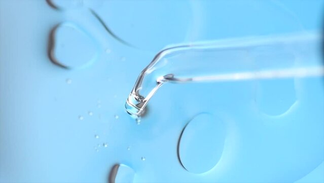 Cosmetic dropper, glass pipette with serum, beauty cosmetics dripping, on blue background. Macro shot. Serum, peptides, beauty and health care products. liquid enzymes close up. Top view. Skin care. 