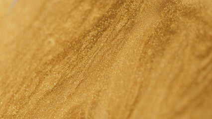 Glitter fluid. Paint flow. Enamel drip. Defocused shiny shimmering golden color wet particles texture ink wave on green creative art abstract background with free space.