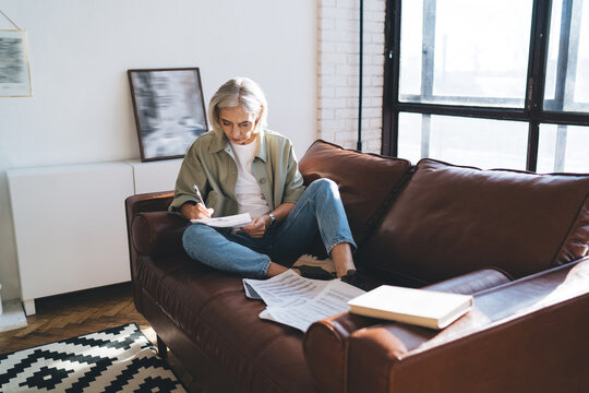 Concentrated senior woman writing notes on paper at home