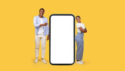Smiling black couple near giant phone with blank screen