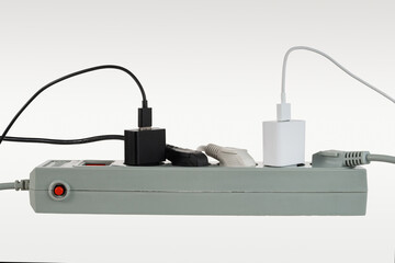 Various electrical plugs from electrical appliances connected to an extension cord isolated on a white background