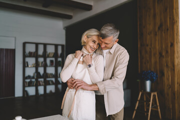 Happy elderly couple hugging at home