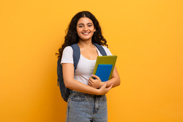 Positive indian woman student holding notebooks looking at copy space - obrazy, fototapety, plakaty