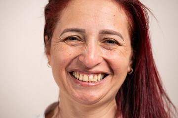 Close up portrait, woman with red hair looking at camera and smiling on pastel background.