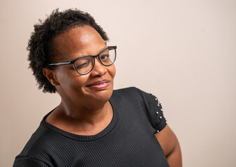 Black woman wearing glasses winking and smiling on pastel background.
