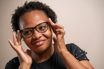 Black woman touching on her glasses on pastel background.