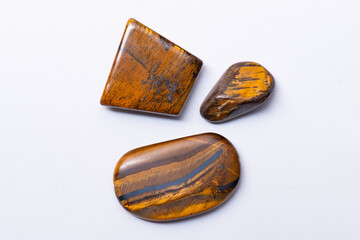 Studio close up photo of three tumbled tiger's eye stones on white background