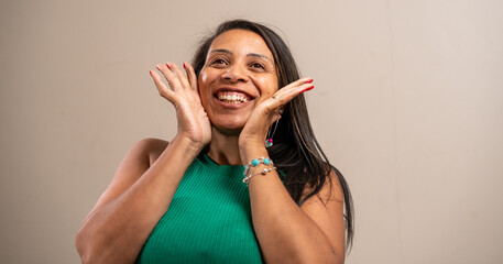 Woman smiling with hands on face on pastel background.
