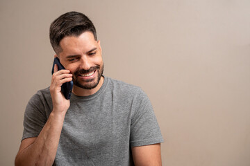 Smiling man talking on cell phone on pastel background.