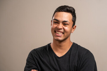 Obraz premium Young man with oriental features smiling on pastel background.