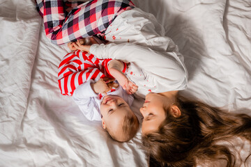 two little girls sisters in New Year's pajamas are lying in bed hugging, top view