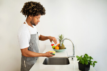 Black man washes dishes at kitchen sink at home