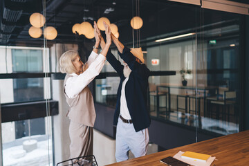 Happy senior employee giving high five in office
