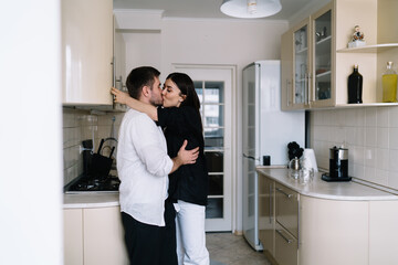 Happy couple hugging and kissing in kitchen