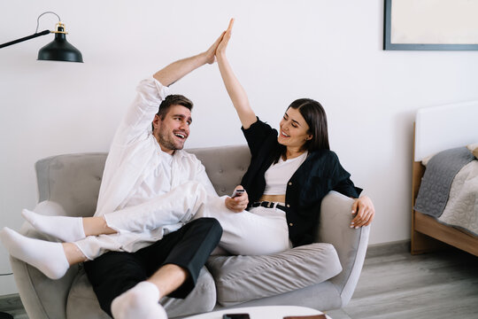 Happy couple resting on sofa and touching hands