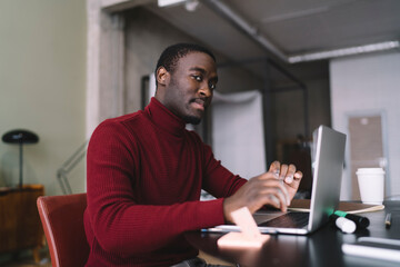 Confident African American man browsing laptop during remote work