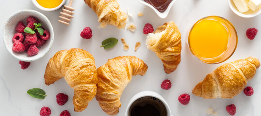 Continental breakfast with croissants, orange juice and cup of coffee on white marble background top view